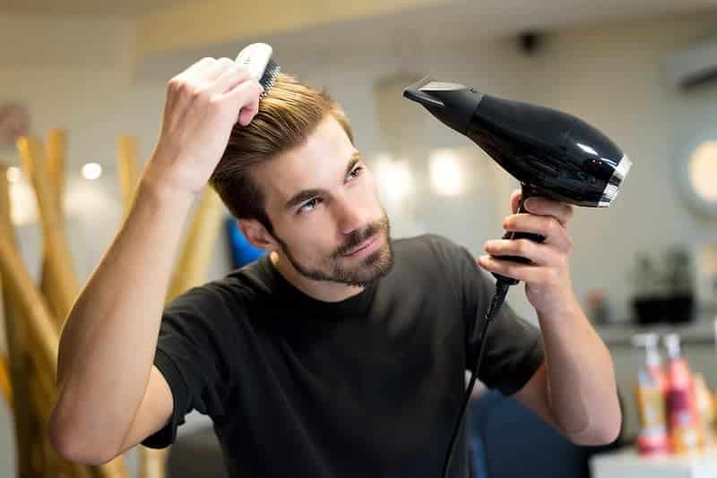 female hairdresser combing and drying his own hair in hair salon 800x800 1