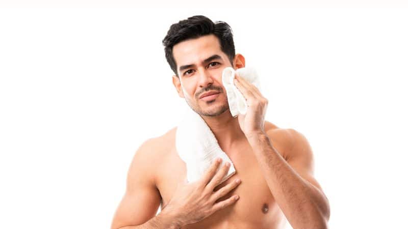 Handsome young man wiping his face with towel